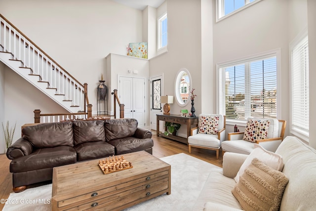 living area featuring stairway, wood finished floors, and a towering ceiling