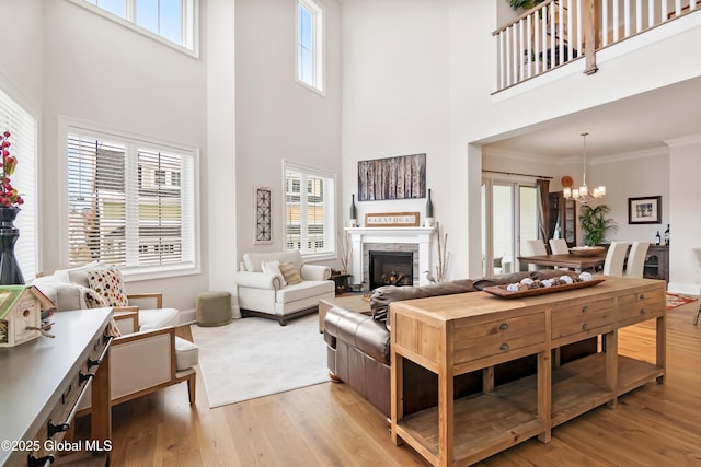 living area with a chandelier, a healthy amount of sunlight, light wood-style floors, and ornamental molding