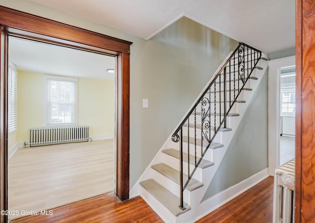 stairs featuring radiator and hardwood / wood-style floors