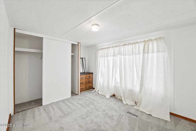 unfurnished bedroom featuring a closet, carpet, and a textured ceiling