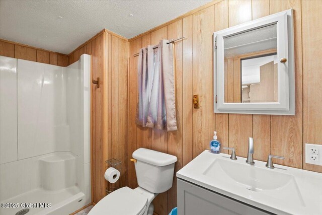 bathroom with vanity, a textured ceiling, wooden walls, and a shower