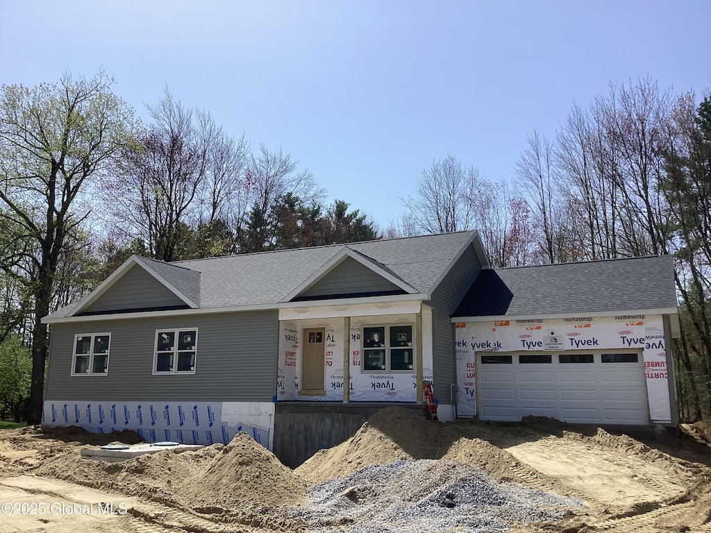 view of front of house with a porch, a garage, and dirt driveway