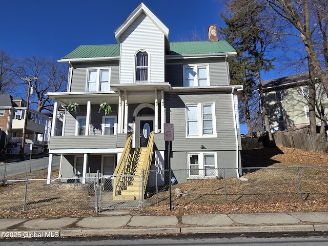 view of front facade featuring metal roof, a fenced front yard, and a chimney