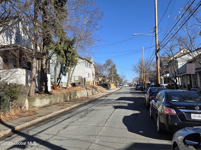 view of street featuring sidewalks, a residential view, curbs, and street lights