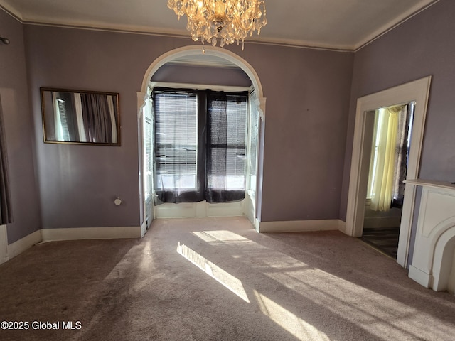 interior space featuring crown molding, carpet flooring, a notable chandelier, and baseboards