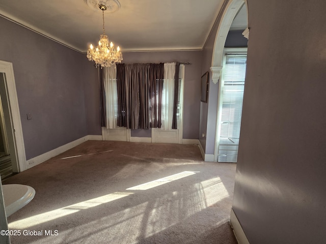 interior space with carpet floors, a notable chandelier, baseboards, and ornamental molding