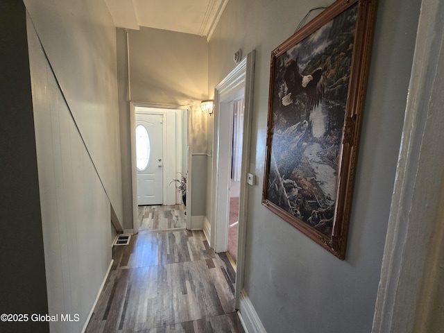 doorway with baseboards, visible vents, and wood finished floors