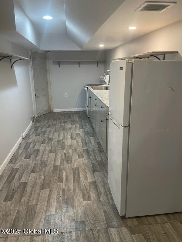 kitchen with light countertops, freestanding refrigerator, visible vents, and wood finished floors