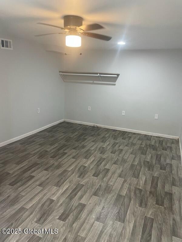 spare room featuring ceiling fan, wood finished floors, visible vents, and baseboards