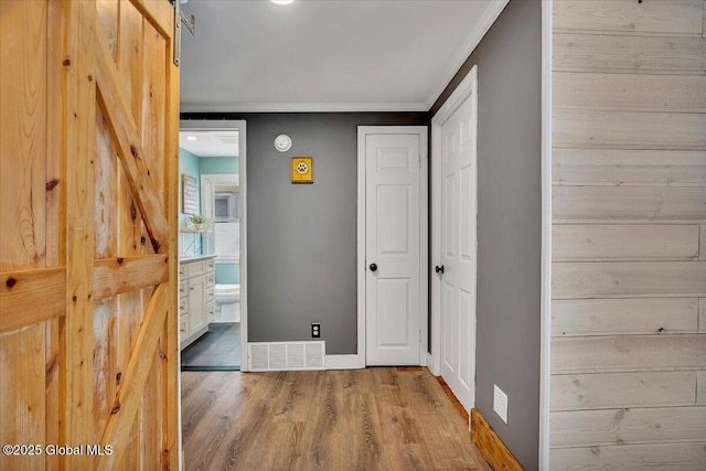 corridor featuring crown molding, a barn door, and light hardwood / wood-style floors