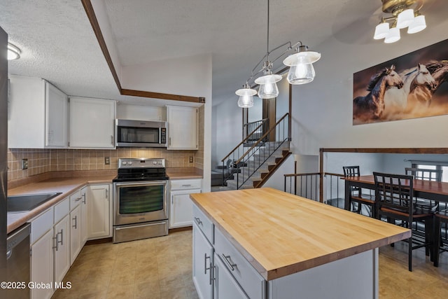 kitchen featuring butcher block counters, backsplash, appliances with stainless steel finishes, white cabinetry, and a sink