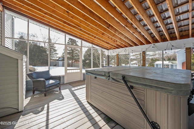 sunroom with lofted ceiling, a jacuzzi, and a healthy amount of sunlight