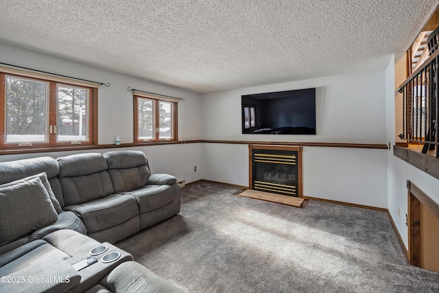 carpeted living room with a textured ceiling, a glass covered fireplace, and baseboards