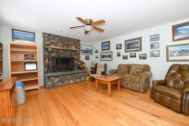 living room with ceiling fan, a fireplace, and light hardwood / wood-style floors