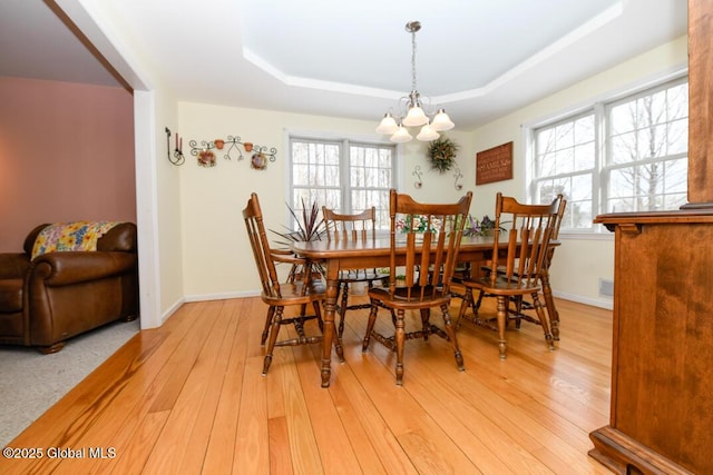 dining area featuring a wealth of natural light, light wood-type flooring, and a tray ceiling