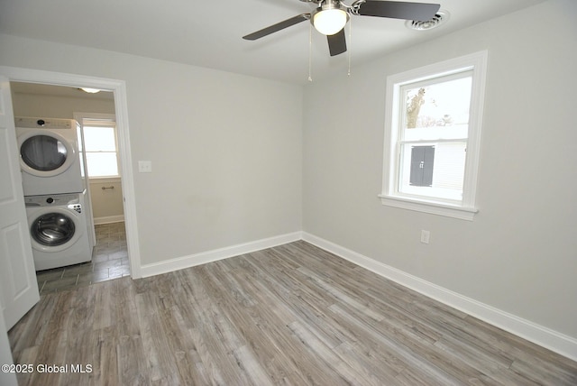 laundry room with ceiling fan, stacked washer / drying machine, and light wood-type flooring