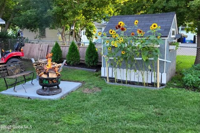 view of yard with a shed, an outdoor fire pit, an outdoor structure, and fence