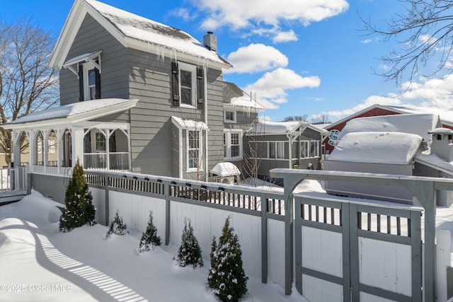 exterior space featuring a porch, a fenced front yard, and a chimney