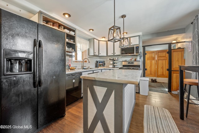 kitchen with open shelves, a kitchen island, light countertops, black appliances, and pendant lighting