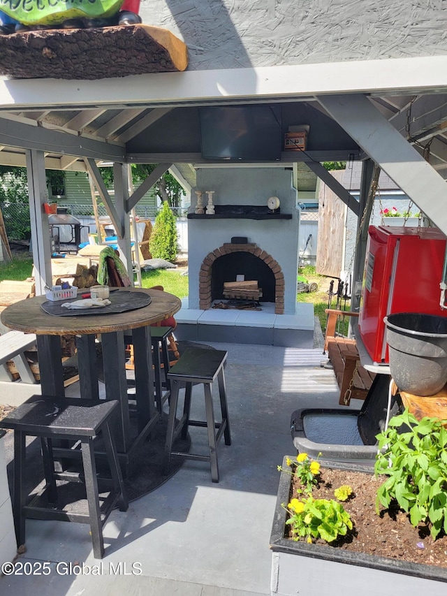 view of patio / terrace featuring an outdoor brick fireplace and a gazebo