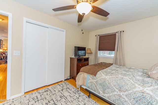 bedroom with ceiling fan, light hardwood / wood-style floors, and a closet