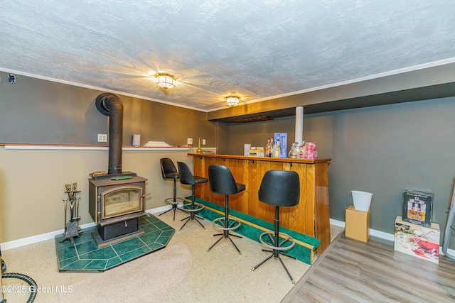 bar with hardwood / wood-style flooring, crown molding, a wood stove, and a textured ceiling