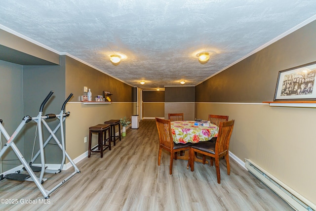 dining space featuring baseboard heating, ornamental molding, a textured ceiling, and light wood-type flooring