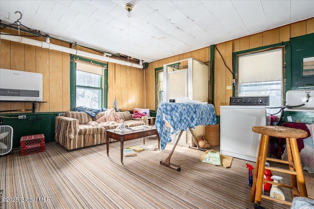 carpeted living room with washer / dryer, a wall mounted air conditioner, and wooden walls