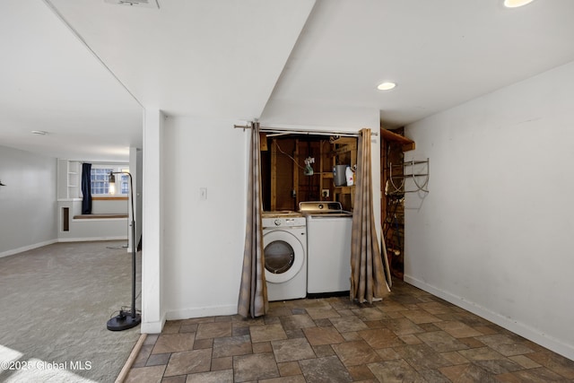 clothes washing area featuring laundry area, washing machine and dryer, baseboards, and stone finish flooring