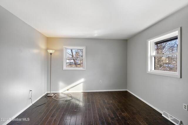 unfurnished room featuring visible vents, a healthy amount of sunlight, baseboards, and hardwood / wood-style flooring