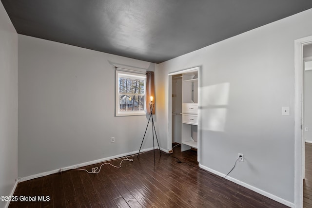 unfurnished bedroom featuring baseboards, wood-type flooring, and a closet