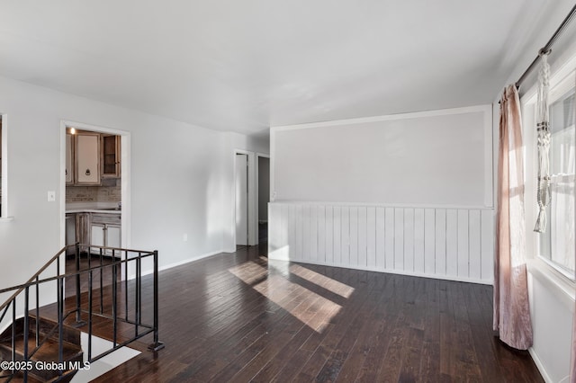 unfurnished room featuring baseboards and dark wood-style flooring