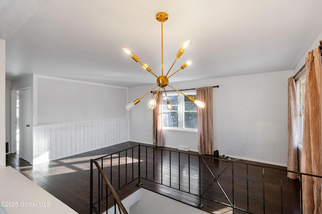 interior space featuring wood finished floors, a chandelier, and wainscoting