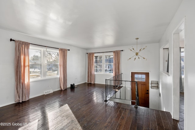 interior space featuring visible vents, baseboards, a notable chandelier, and hardwood / wood-style flooring