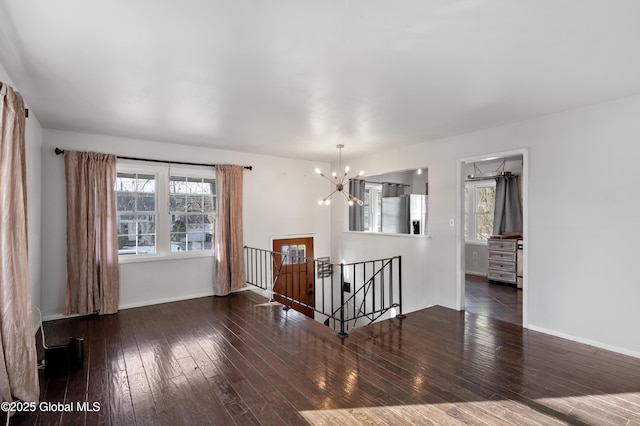 empty room with hardwood / wood-style floors, an inviting chandelier, and baseboards