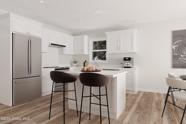 kitchen with under cabinet range hood, a kitchen breakfast bar, white cabinets, light countertops, and stainless steel fridge