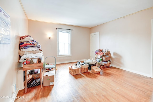 interior space with crown molding, baseboards, and wood finished floors