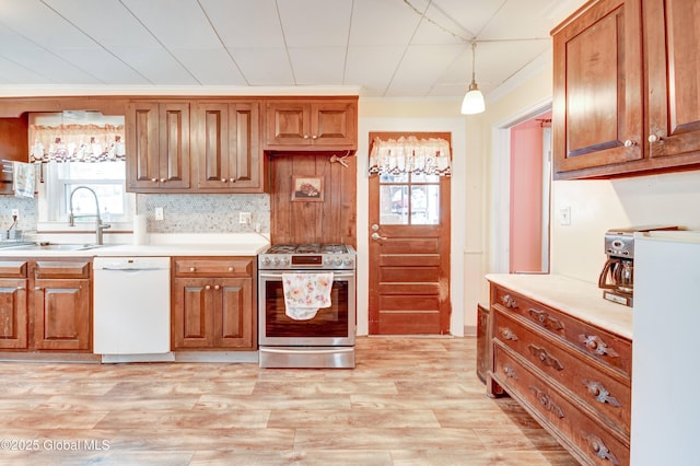 kitchen with decorative backsplash, gas range, light wood-style flooring, white dishwasher, and a sink