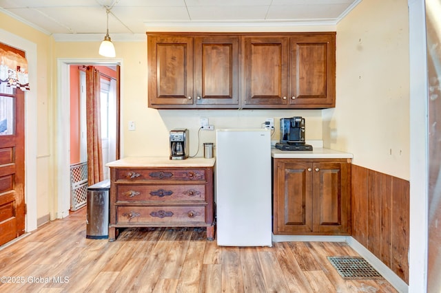 kitchen with light countertops, visible vents, crown molding, and light wood finished floors