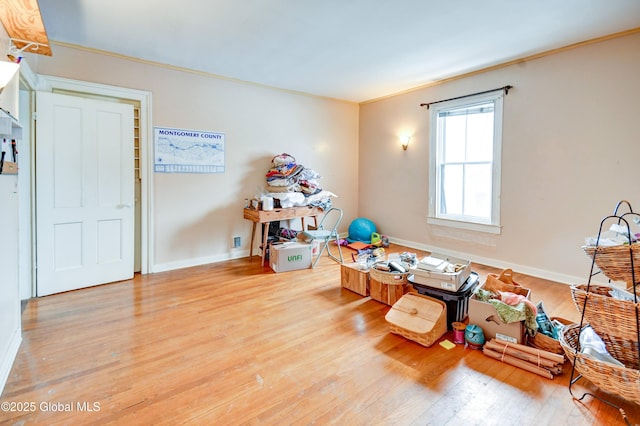 rec room with crown molding, baseboards, and light wood-style floors