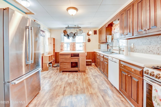 kitchen with light countertops, appliances with stainless steel finishes, light wood-type flooring, and a sink