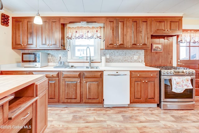 kitchen with stainless steel gas range, light countertops, white dishwasher, and a sink