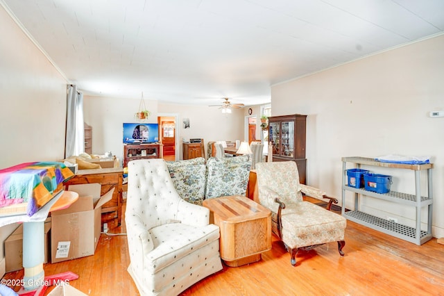 living area with ornamental molding, ceiling fan, and wood finished floors