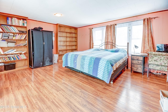 bedroom featuring ornamental molding and wood finished floors