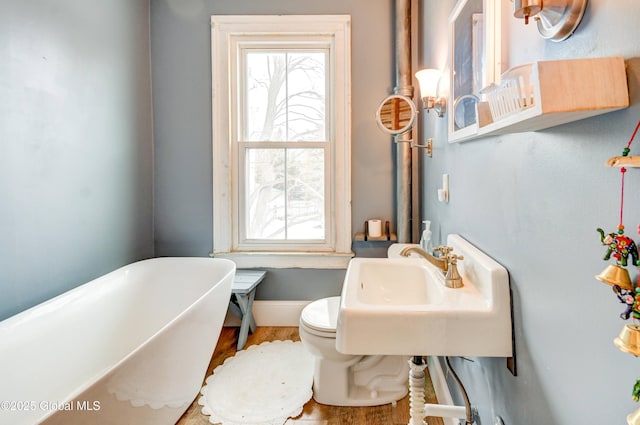 full bathroom with wood finished floors, a freestanding tub, a wealth of natural light, and baseboards