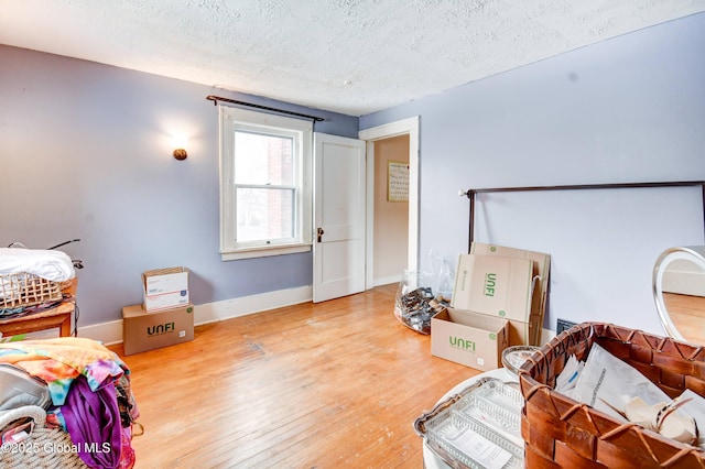 bedroom with a textured ceiling, wood finished floors, and baseboards