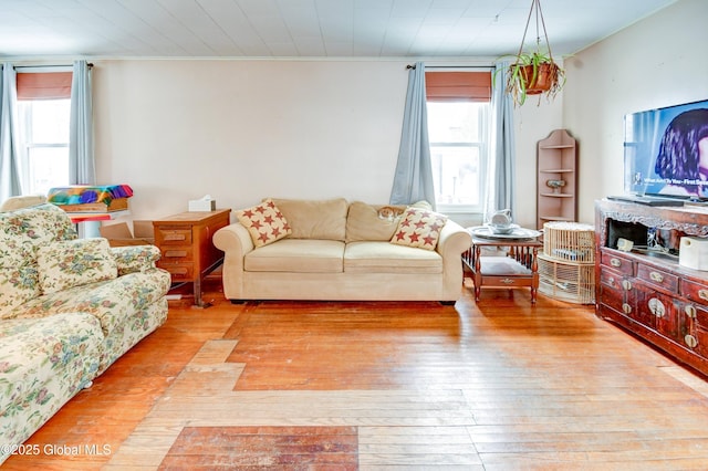 living area with a healthy amount of sunlight, light wood-style flooring, and crown molding