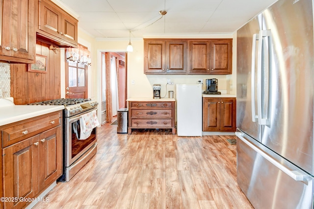 kitchen featuring stainless steel appliances, brown cabinets, ornamental molding, and light wood-style flooring