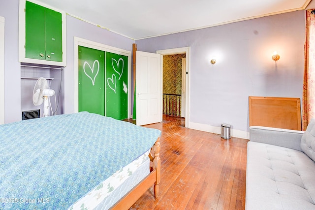 bedroom featuring a closet, wood-type flooring, visible vents, and baseboards