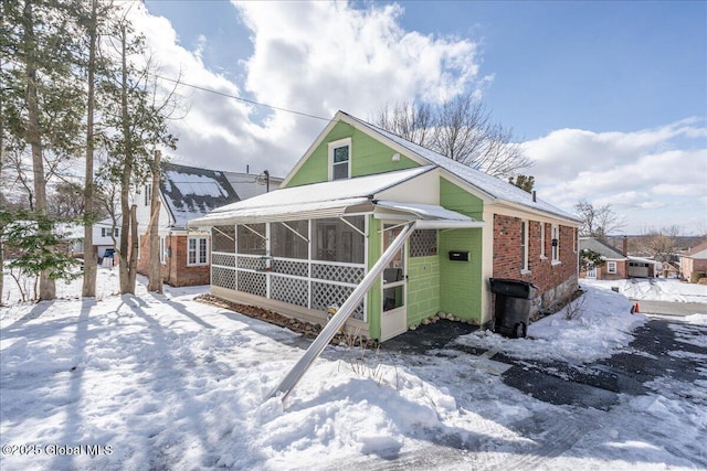 view of front of house with brick siding and a sunroom